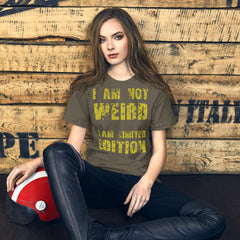Unisex t-shirt with "I Am Not Weird, I Am Limited Edition" yellow text design, worn by a seated model against a rustic wooden background.