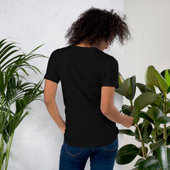 Unisex black t-shirt with purple "I am not Weird" text, worn by a model near plants.