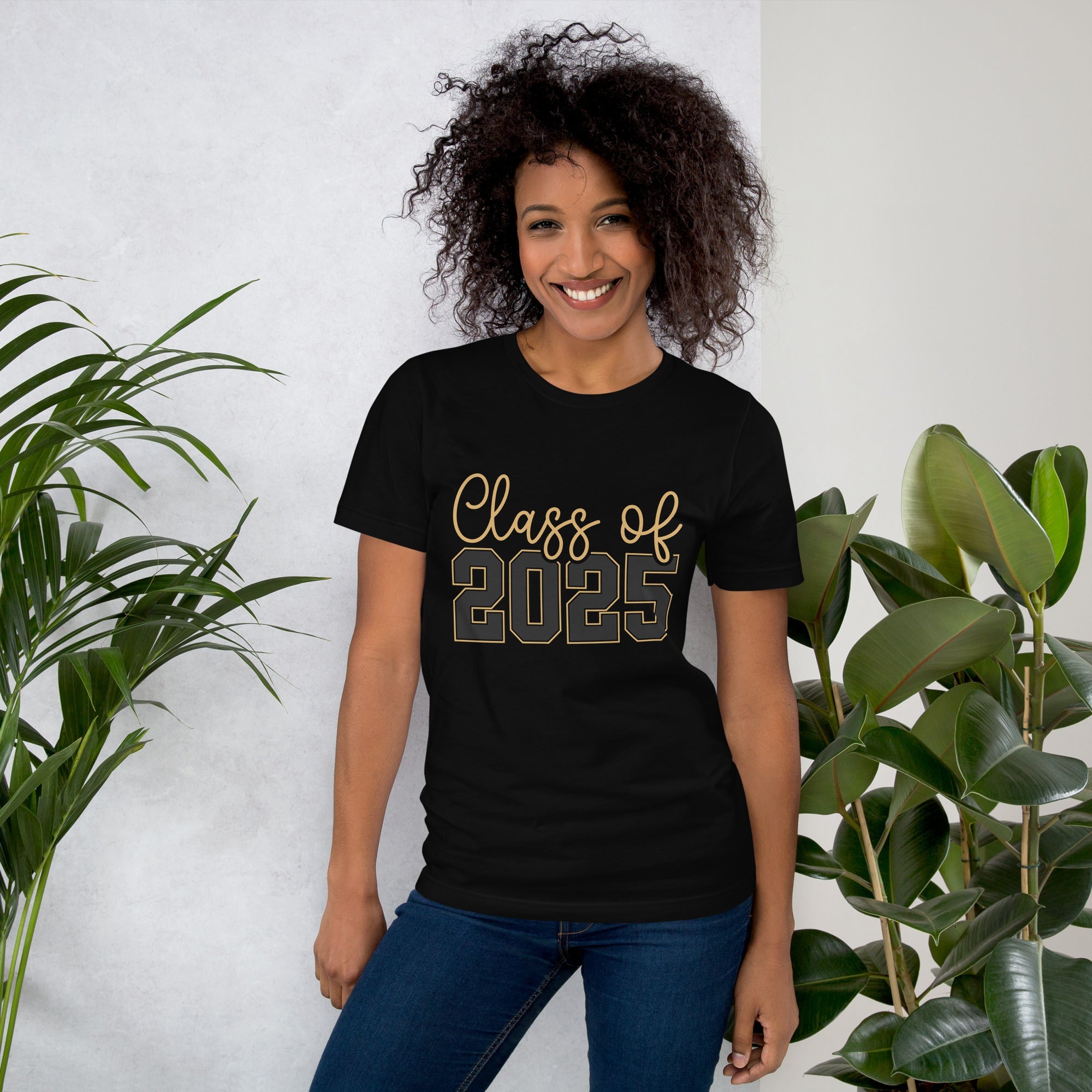 Class of 2025 unisex t-shirt with gold lettering worn by a smiling person standing indoors.