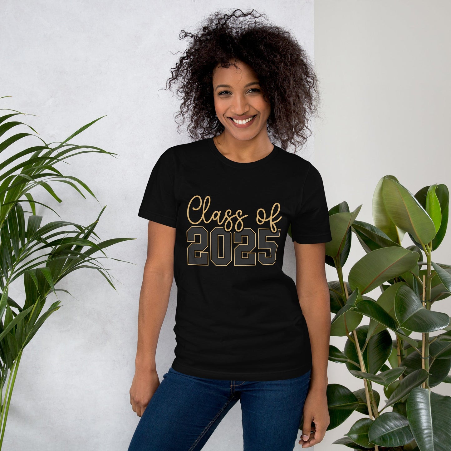 Class of 2025 unisex t-shirt with gold lettering worn by a smiling person standing indoors.