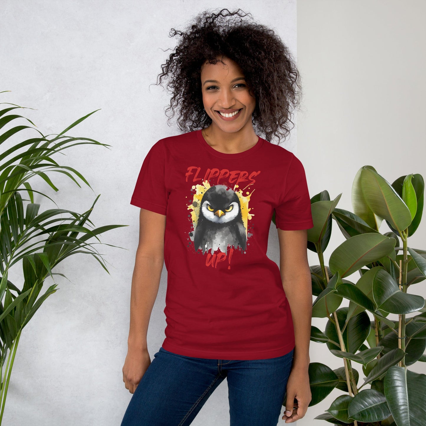 Unisex t-shirt with "Flippers Up" graphic, featuring a penguin on a red background, worn by a woman.