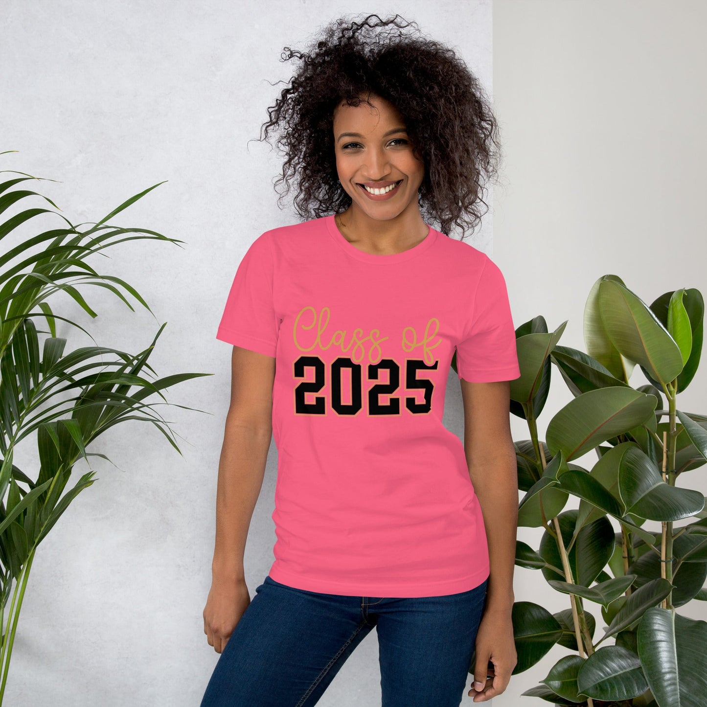Unisex pink t-shirt with "Class of 2025" print, worn by a smiling person surrounded by plants.