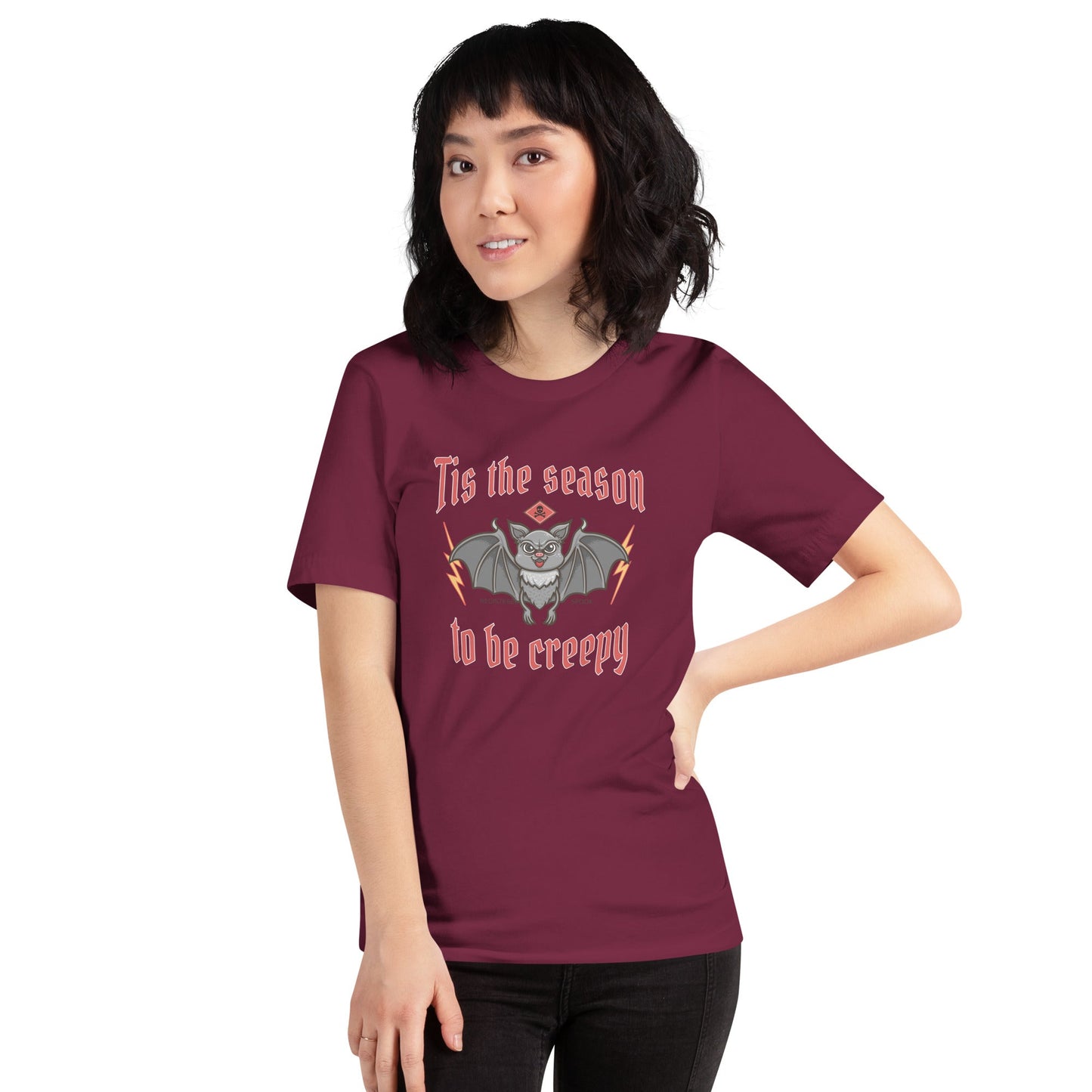 Unisex t-shirt with "Tis the season to be creepy" design, featuring a spooky character illustration on a comfortable, maroon fabric.