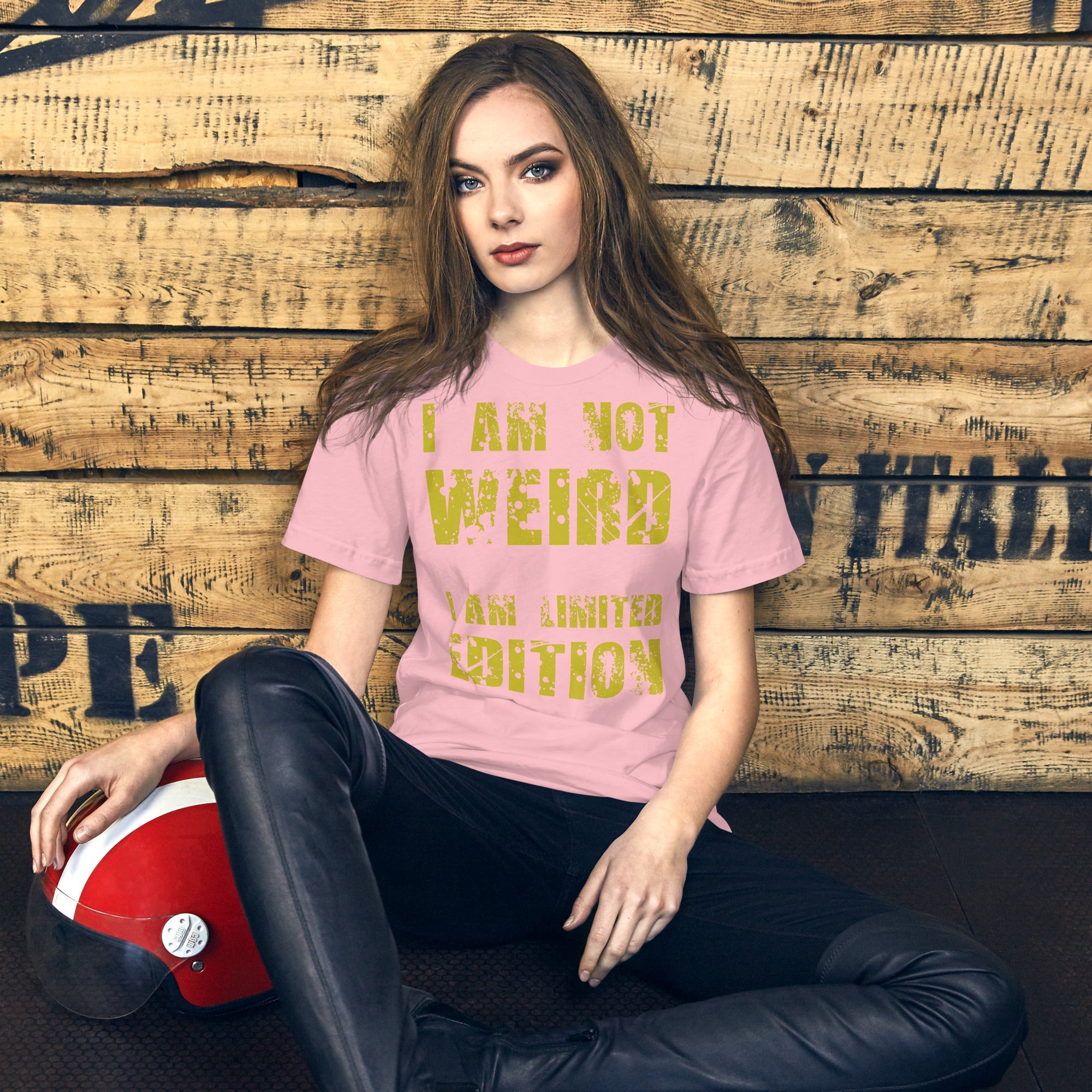 Unisex t-shirt with "I Am Not Weird" in yellow text, worn by a person sitting against a wooden backdrop.