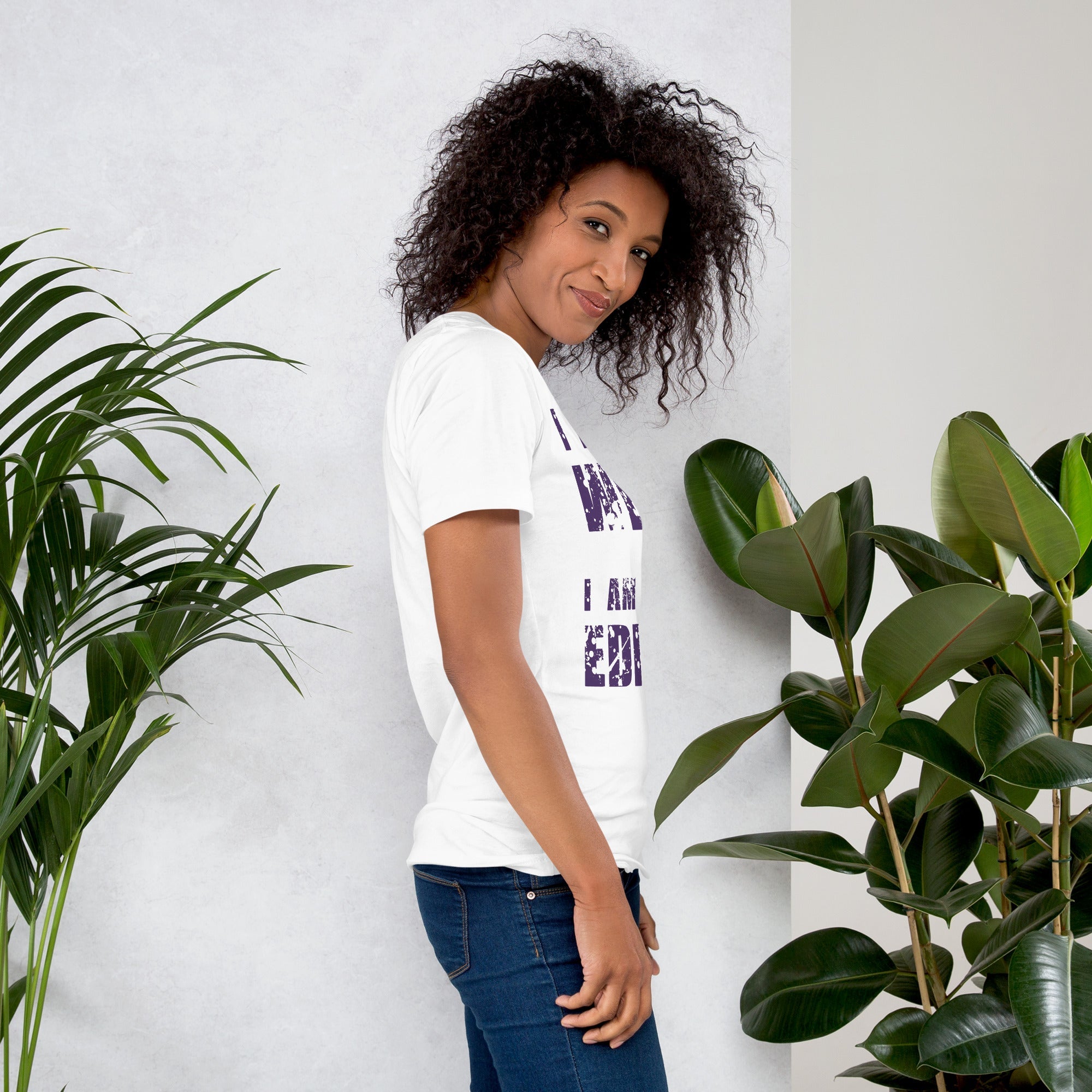 Woman wearing "I am not Weird" unisex t-shirt in purple text with plants in background.