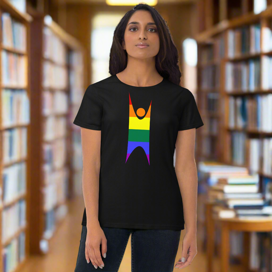 Pride rainbow women's t-shirt with happy human design in a library setting.