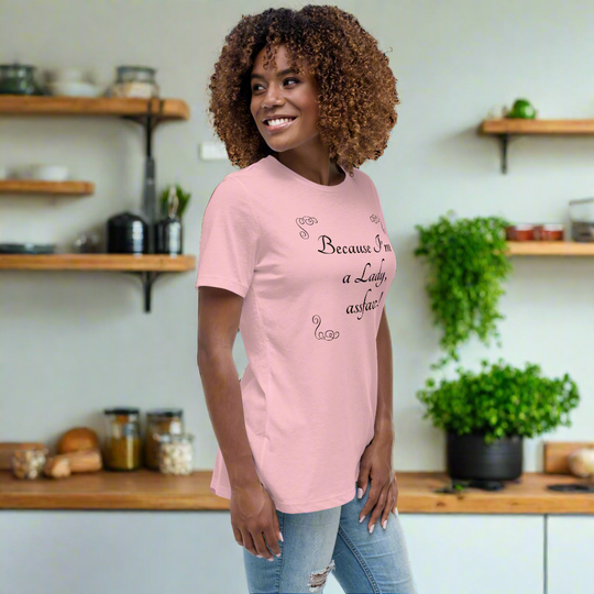 Woman wearing "Because I'm a Lady, Assface!" pink relaxed t-shirt in a kitchen setting.