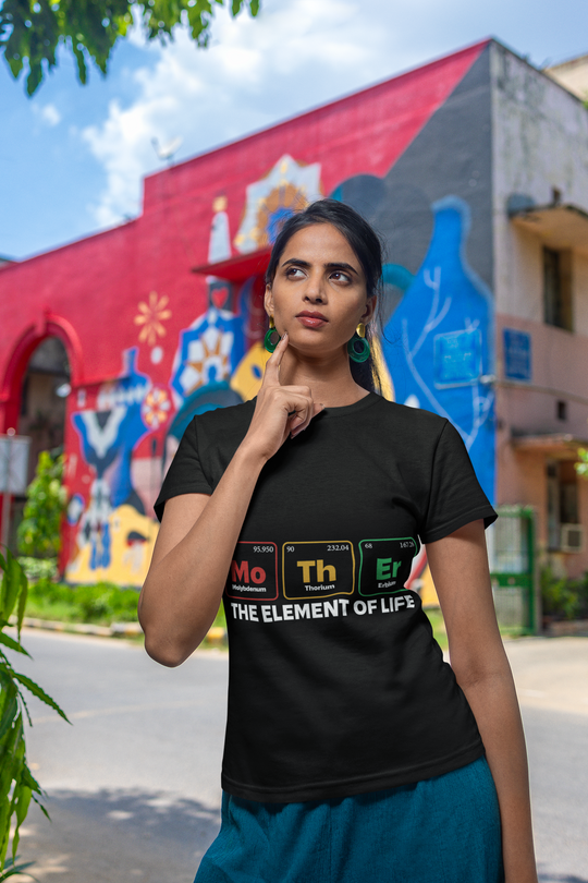 Dark unisex t-shirt with "Mother - the Element of Life" design, soft and lightweight, worn by a person against a colorful urban backdrop.
