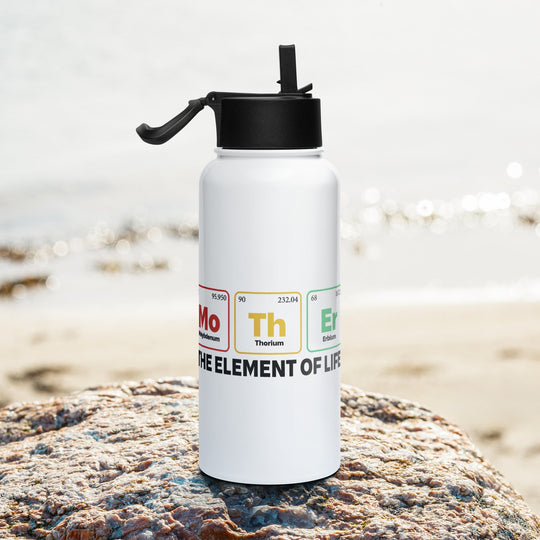 Stainless steel water bottle with straw lid, featuring "Mother - the Element of Life" design, on a rock by the beach.