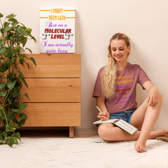 Unisex t-shirt with "I might seem lazy but at a molecular level I am actually quite busy" text, worn by seated woman; soft, lightweight fabric, ideal for adults.