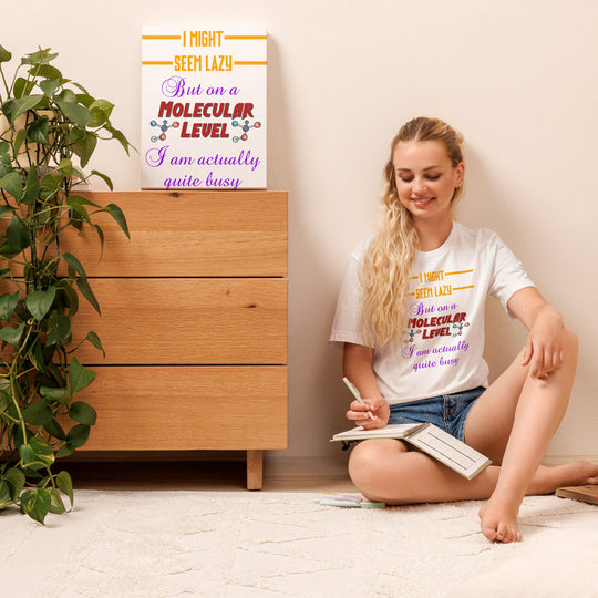 Unisex t-shirt with humorous molecular level design, worn by a person sitting in a cozy room setting.