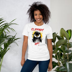 Unisex t-shirt with "Flippers Up" design featuring a playful penguin graphic, worn by a smiling person standing indoors.