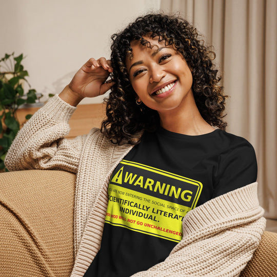 Women's relaxed t-shirt featuring "Warning! Scientifically Literate Individual" design, worn by smiling woman in cozy indoor setting.