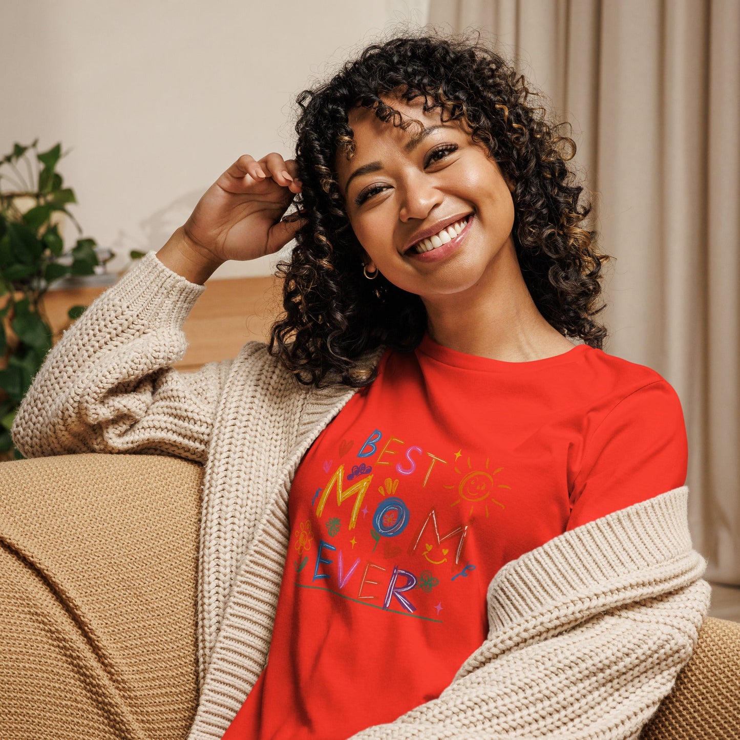 Smiling woman wearing "Best Mom Ever" red relaxed t-shirt with cardigan.